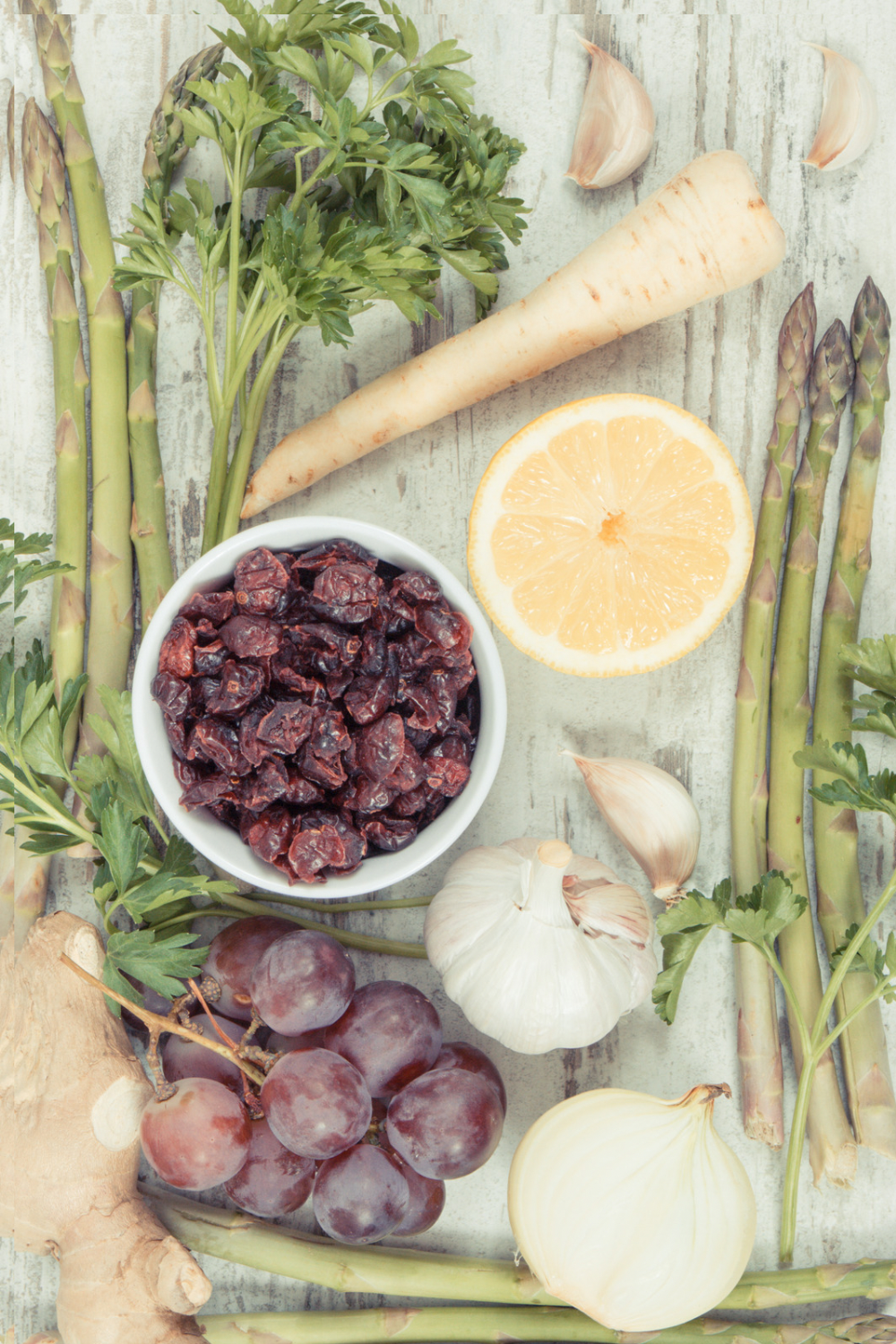 parsley, dates, parsnip, orange, grapes, asparagus, garlic and ginger on a rustic table