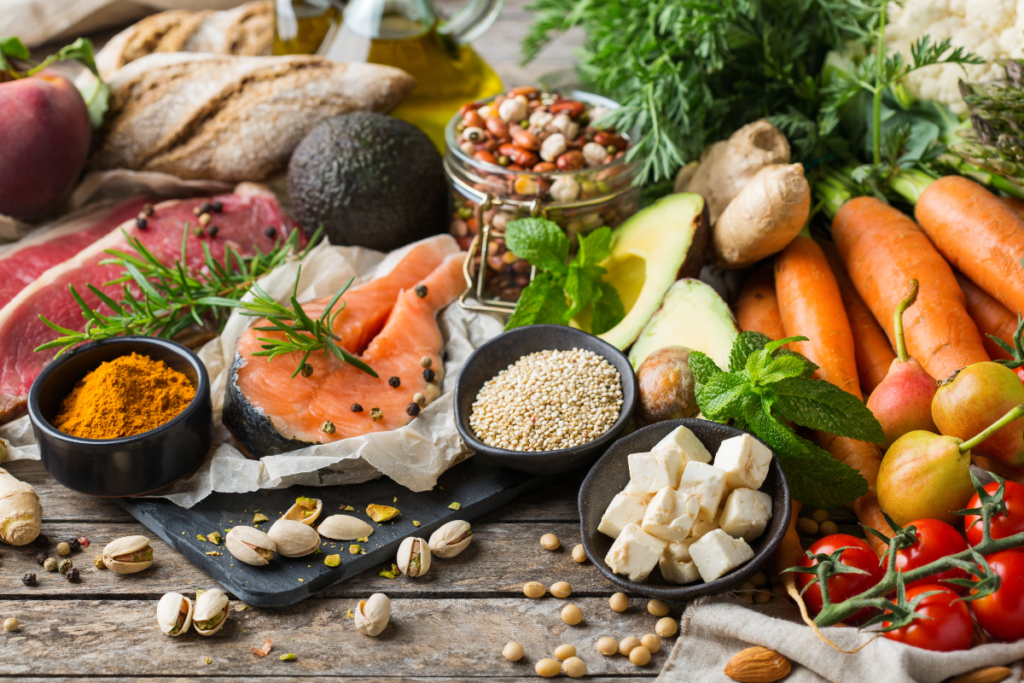 A spread of nutrienet dense vegetables, fish and meat on a wooden surface