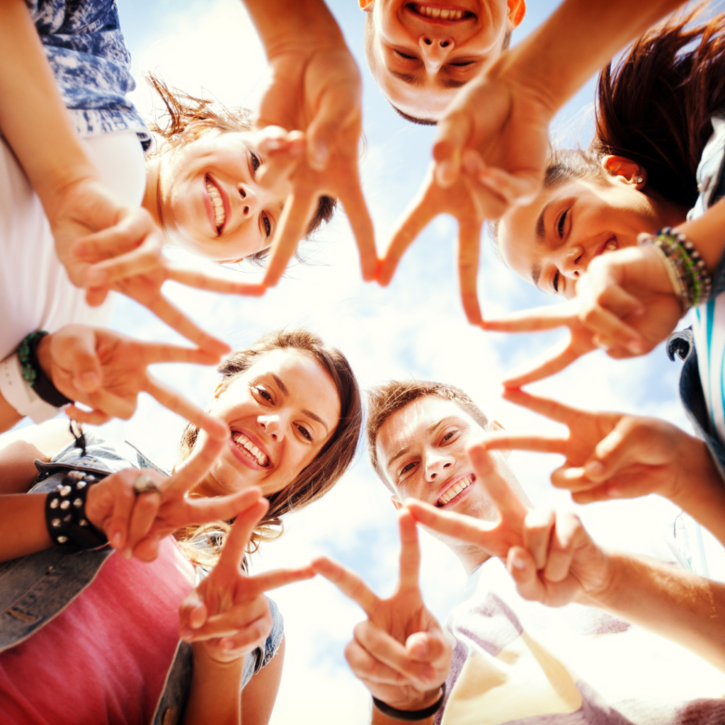 a group of teenagers looking down at the camera smiling and using their fingers to create a star shape