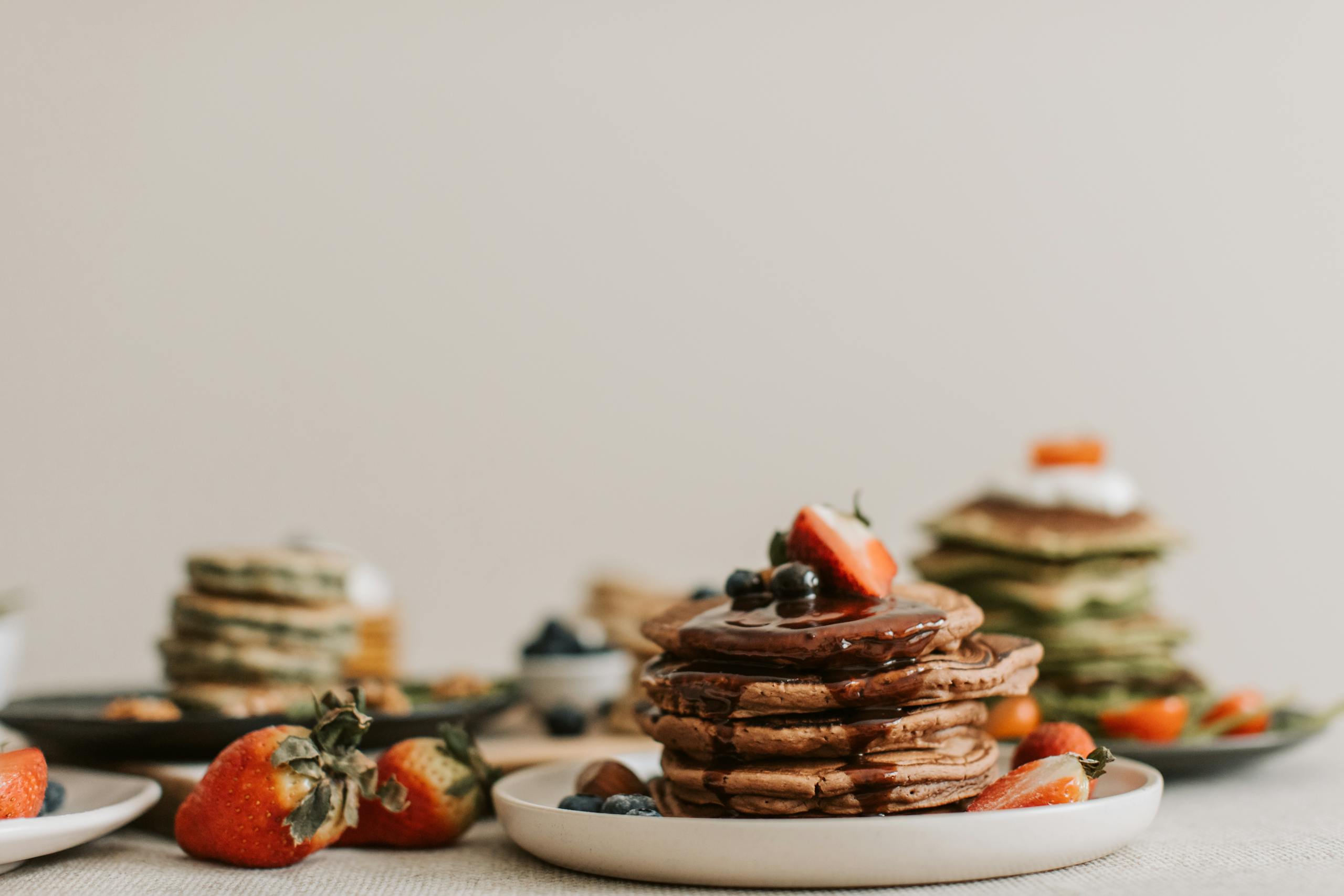 Stack of pancakes topped with fresh strawberries and blueberries, creating a mouthwatering breakfast scene.